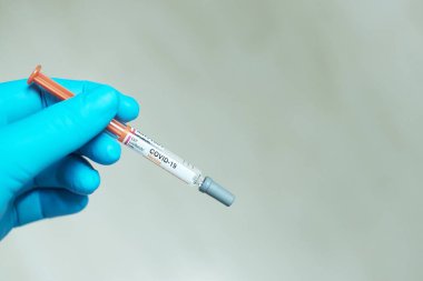 Mavi eldivenli doktor eli ve Covid-19 aşısı. 