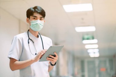 Ameliyat maskesi ve tableti olan Asyalı doktor hastanede.