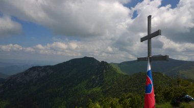 Dağın tepesinde bayrağı olan bir mezar. 