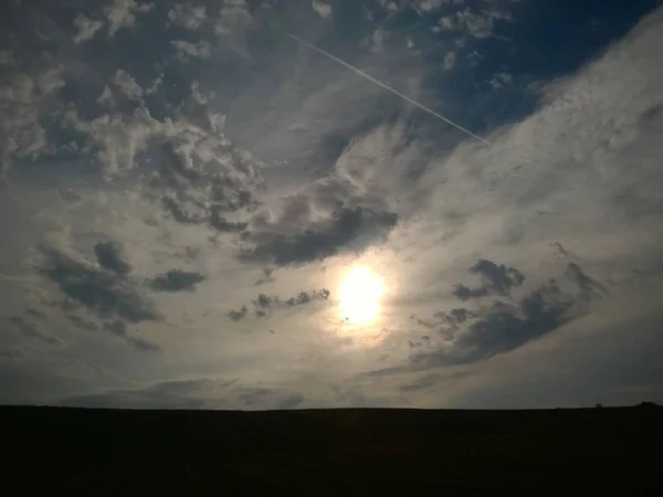 Sun in cloudy sky over meadow