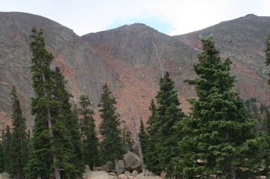 Bir yaz veya ilkbahar gününde bulutlar ve dökmeyen ağaçlar ile Dağ manzara