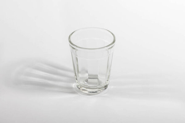 close up view of empty glass and shadow on light background