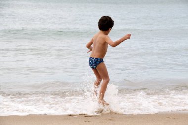küçük çocuk deniz dalgaları üzerinde atlama 