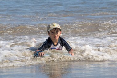 deniz dalgalarında yüzen giysiler içinde küçük çocuk 