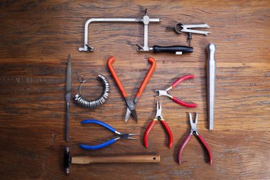 Kuyumcular takı işyerinde araçları üst görünümü. Profesyonel araçlar la zanaat takı yapmak için Masaüstü. Rustik ahşap arka plan üzerinde araç seti