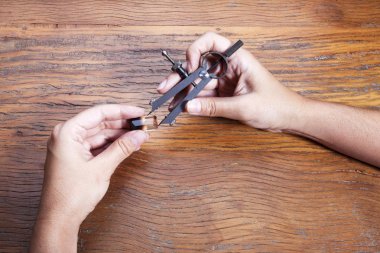 El kuyumcular takı işyerinde araçları tutar. Kuyumcu mücevher işinde. Ahşap arka plan üzerinde profesyonel bir araç ile zanaat takı yapma