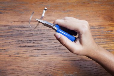 El kuyumcular takı işyerinde araçları tutar. Kuyumcu mücevher işinde. Ahşap arka plan üzerinde profesyonel bir araç ile zanaat takı yapma