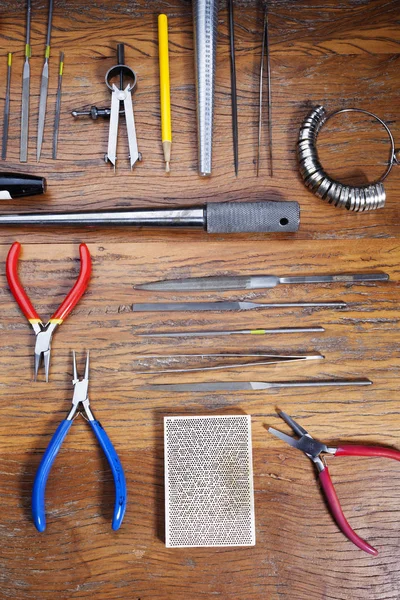 Kuyumcular takı işyerinde araçları üst görünümü. Profesyonel araçlar la zanaat takı yapmak için Masaüstü. Rustik ahşap arka plan üzerinde araç seti