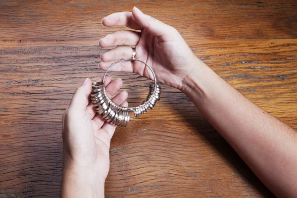 Hand holds a goldsmiths tools on the jewelry workplace. Jeweler at work in jewelry. Craft jewelry making with professional tool over wooden background