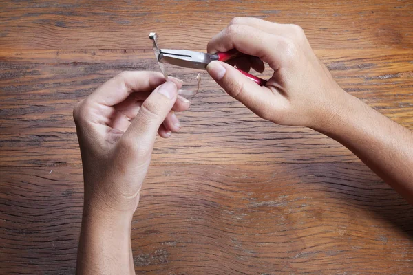 Hand holds a goldsmiths tools on the jewelry workplace. Jeweler at work in jewelry. Craft jewelry making with professional tool over wooden background