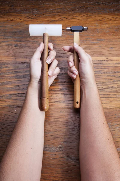 Hand holds a goldsmiths tools on the jewelry workplace. Jeweler at work in jewelry. Craft jewelry making with professional tool over wooden background