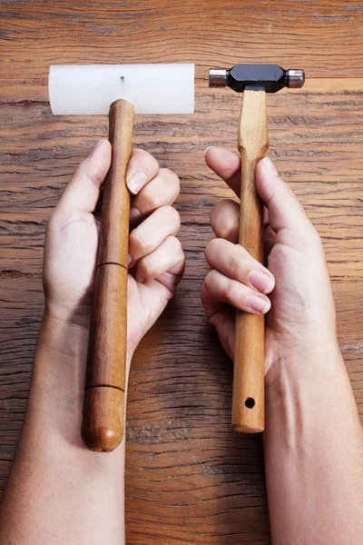 Hand holds a goldsmiths tools on the jewelry workplace. Jeweler at work in jewelry. Craft jewelry making with professional tool over wooden background