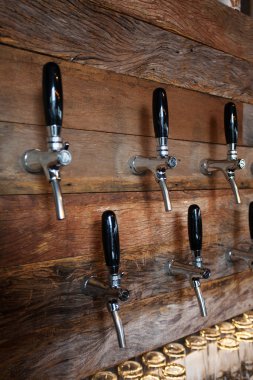 Bardaki bira muslukları. Alkol konsepti. Eski tarz. Ahşap arka planda bira işi. Işıklar ve gölgeler. 