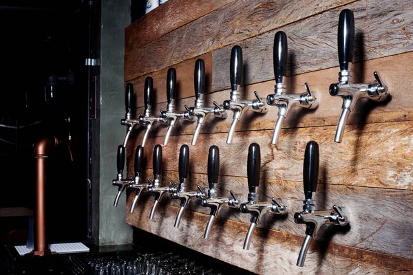 The beer taps in a pub. Alcohol concept. Vintage style. Beer craft over wooden background. Lights and shadows.