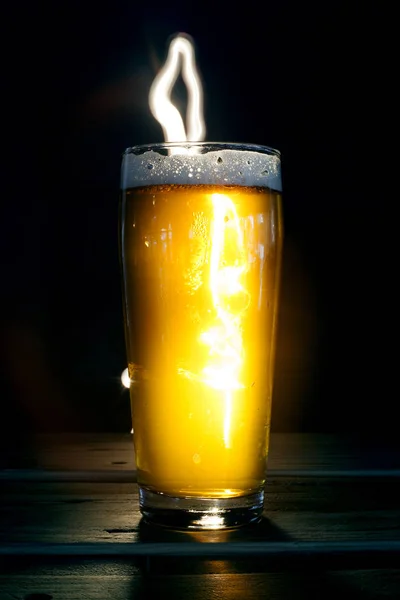 Close up Beer Glass with Light painting background. Amazing abstract colored lights in motion. Magical light in a glass of craft beer.