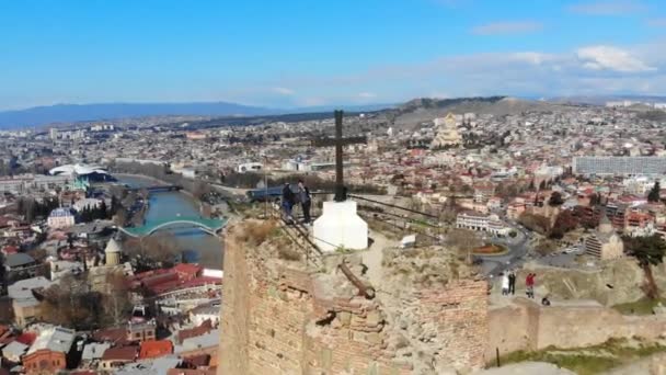 4k vista aérea de la cima de la fortaleza de Narikala, cruz y turistas en el pico — Vídeo de stock