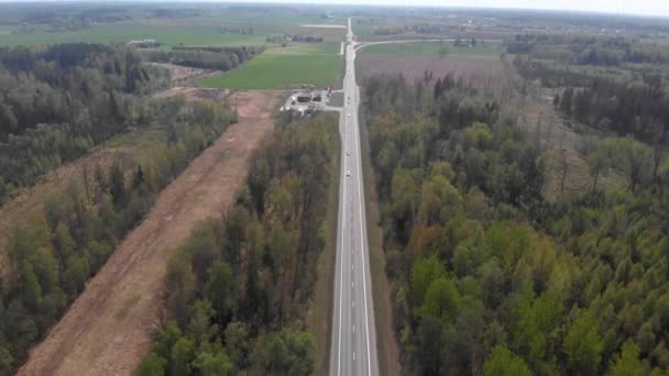 4k vista aérea da estrada no meio da faixa florestal com trânsito em movimento à luz do dia — Vídeo de Stock