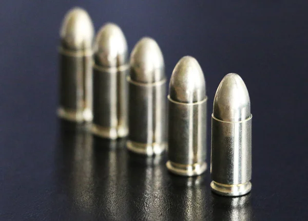 Pistol bullets lined up on black background