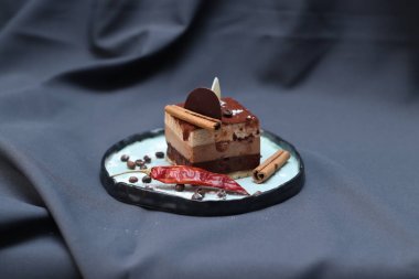 Alışılmadık bir tabak, mavi-gri kumaş arka plan üzerinde kahve ve tarçın ile Çikolatalı kek