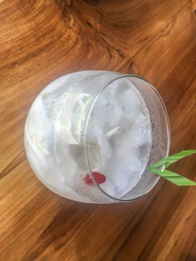 Taze hindistan cevizi suyu Bardak, doğal serin hindistan cevizi suyu içmek. Endonezya Buz hindistan cevizi içecek veya kelapa muda cam üzerinde yaprak ile izole ahşap arka plan