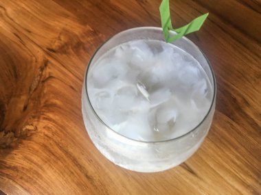 Taze hindistan cevizi suyu Bardak, doğal serin hindistan cevizi suyu içmek. Endonezya Buz hindistan cevizi içecek veya kelapa muda cam üzerinde yaprak ile izole ahşap arka plan