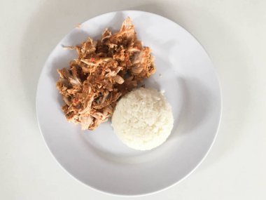 Beyaz arka planda izole edilmiş beyaz tabakta kırmızı biberli ve sarımsak aromalı Ayam geprek veya baharatlı tavuk ezmesi. Endonezya mutfağı baharatlı yemekleri