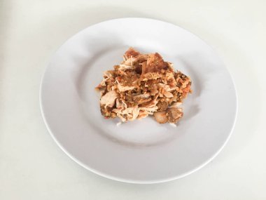 Beyaz arka planda izole edilmiş beyaz tabakta kırmızı biberli ve sarımsak aromalı Ayam geprek veya baharatlı tavuk ezmesi. Endonezya mutfağı baharatlı yemekleri