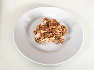 Beyaz arka planda izole edilmiş beyaz tabakta kırmızı biberli ve sarımsak aromalı Ayam geprek veya baharatlı tavuk ezmesi. Endonezya mutfağı baharatlı yemekleri