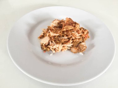 Beyaz arka planda izole edilmiş beyaz tabakta kırmızı biberli ve sarımsak aromalı Ayam geprek veya baharatlı tavuk ezmesi. Endonezya mutfağı baharatlı yemekleri