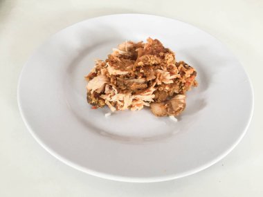 Beyaz arka planda izole edilmiş beyaz tabakta kırmızı biberli ve sarımsak aromalı Ayam geprek veya baharatlı tavuk ezmesi. Endonezya mutfağı baharatlı yemekleri