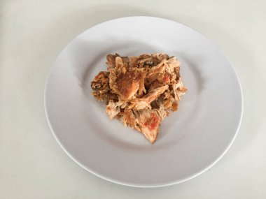 Beyaz arka planda izole edilmiş beyaz tabakta kırmızı biberli ve sarımsak aromalı Ayam geprek veya baharatlı tavuk ezmesi. Endonezya mutfağı baharatlı yemekleri