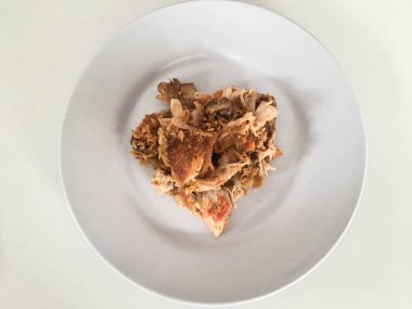 Beyaz arka planda izole edilmiş beyaz tabakta kırmızı biberli ve sarımsak aromalı Ayam geprek veya baharatlı tavuk ezmesi. Endonezya mutfağı baharatlı yemekleri