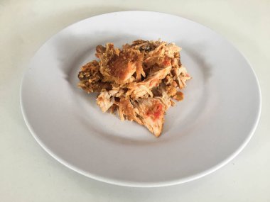 Beyaz arka planda izole edilmiş beyaz tabakta kırmızı biberli ve sarımsak aromalı Ayam geprek veya baharatlı tavuk ezmesi. Endonezya mutfağı baharatlı yemekleri