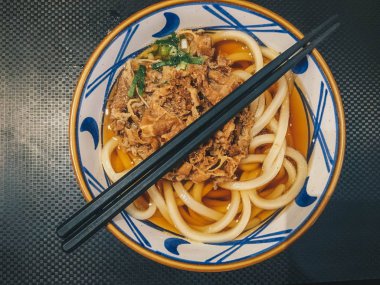 Biraz etli Japon yemeğinin Udon eriştesi. Siyah arka plan üzerinde izole masada bir kase yakın çekim. yukarıdan yatay üst görünüm 