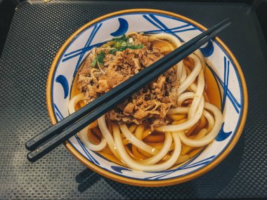 Biraz etli Japon yemeğinin Udon eriştesi. Siyah arka plan üzerinde izole masada bir kase yakın çekim. yukarıdan yatay üst görünüm 