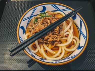 Biraz etli Japon yemeğinin Udon eriştesi. Siyah arka plan üzerinde izole masada bir kase yakın çekim. yukarıdan yatay üst görünüm 