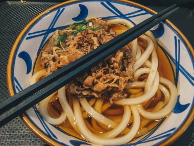 Biraz etli Japon yemeğinin Udon eriştesi. Siyah arka plan üzerinde izole masada bir kase yakın çekim. yukarıdan yatay üst görünüm 