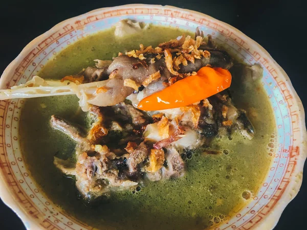 Tengkleng. goat meat with ribs and bone cooked with soup. Indonesian Traditional Food made from Barbecue Lamb\'s Bone isolated on black wood background