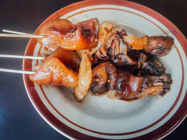 Sate Kambing Goreng veya keçi satay koyu arka plan üzerinde dilimlenmiş arpacık ile biber ve fıstık sosu ile karışık koyun eti yapılan geleneksel Endonezya gıda