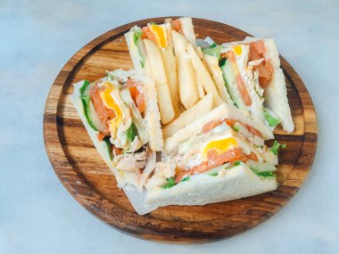 Beyaz arka plan üzerinde izole ahşap tabak üzerinde jambon, yumurta, domates, marul ve beyaz ekmek ile gemide dört sandviç