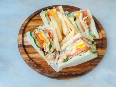 Beyaz arka plan üzerinde izole ahşap tabak üzerinde jambon, yumurta, domates, marul ve beyaz ekmek ile gemide dört sandviç