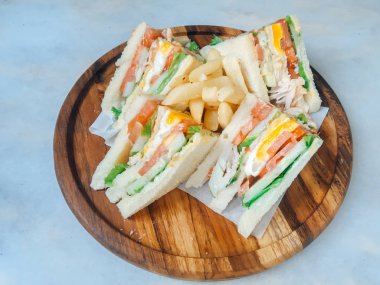 Beyaz arka plan üzerinde izole ahşap tabak üzerinde jambon, yumurta, domates, marul ve beyaz ekmek ile gemide dört sandviç