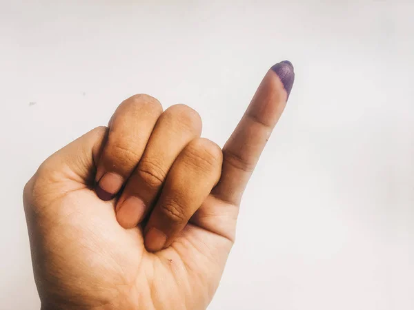 Inked pinky finger of a man hand isolated on white background. Purple ink blots from voters finger provides evidence election (pilkada) Indonesia