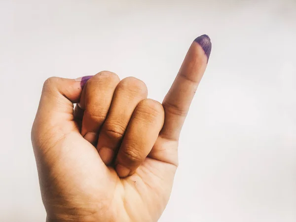 Inked pinky finger of a man hand isolated on white background. Purple ink blots from voters finger provides evidence election (pilkada) Indonesia