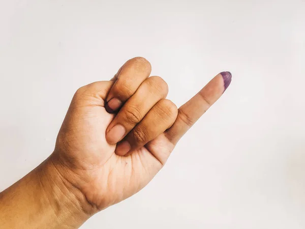 Inked pinky finger of a woman hand isolated on white background. Purple ink blots from voters finger provides evidence election (pemilu) Indonesia