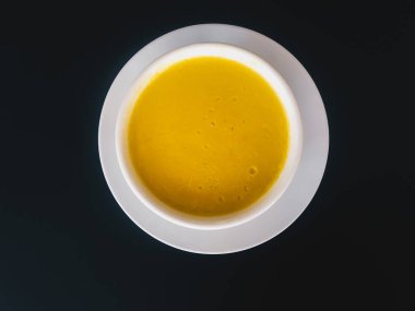 Siyah arka plan üzerinde izole beyaz bir kapta saf sarı kremsi Mısır çorbası. Sağlıklı yiyecekler. Üstte görüntü