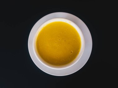 Siyah arka plan üzerinde izole beyaz bir kapta saf sarı kremsi Mısır çorbası. Sağlıklı yiyecekler. Üstte görüntü