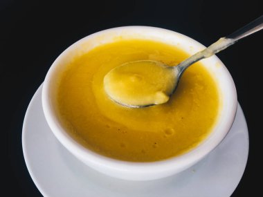 Siyah arka plan üzerinde izole beyaz bir kapta saf sarı kremsi Mısır çorbası. Sağlıklı yiyecekler. Üstte görüntü