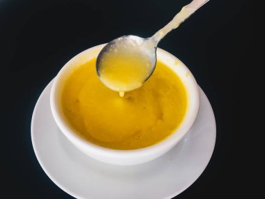 Siyah arka plan üzerinde izole beyaz bir kapta saf sarı kremsi Mısır çorbası. Sağlıklı yiyecekler. Üstte görüntü