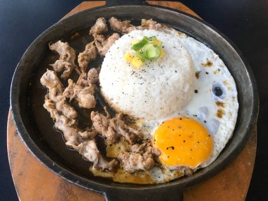 Güneşli kızarmış yumurta ve Izgara Et veya garnitür mısır ve pırasa yakın çekim siyah arka plan üzerinde izole sıcak tabak ile sığır eti ile Pirinç